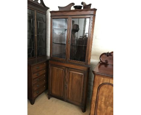 A Victorian mahogany floor-standing corner display cabinet, the glazed upper section having a swan-neck pediment and adjustab