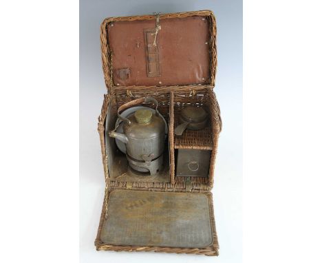 An early 20th century motorists wicker travel tea basket, with kettle and burner, tea infuser and three enamel dishes, some w