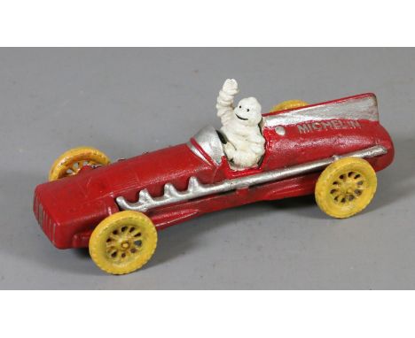 A painted cast metal advertising figure of the Michelin man in a vintage racing car.