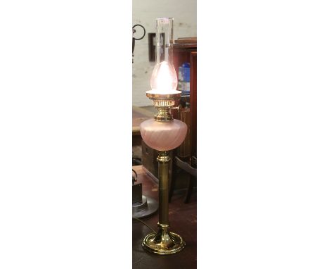 A 230 volt brass based column tablelamp in the form of a Victorian oil lamp with pink glass font.