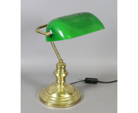 A brass based desk lamp with green glass shade.