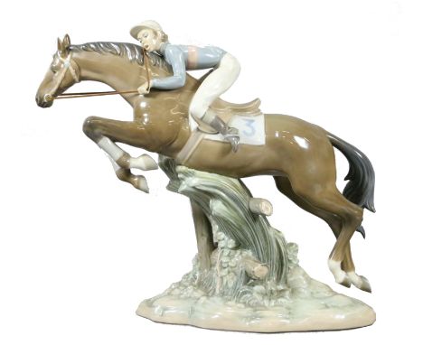 A large Lladro model of a race horse and jockey vaulting a fence.