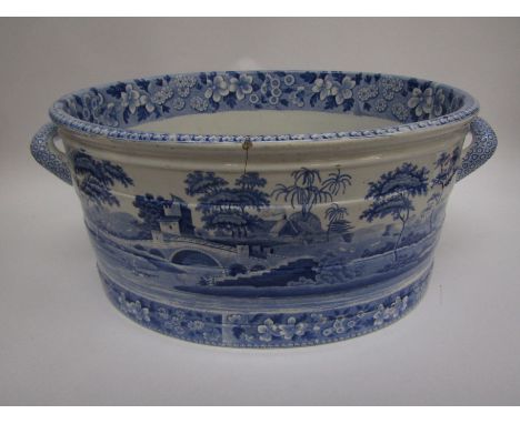 A mid 19th Century Spode blue and white foot bath with country house scene, floral borders, twin handles, cracked