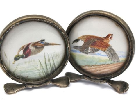 Two George V novelty silver mounted menu holders, each with watercolours behind glazed fronts, one depicting a Partridge, oth