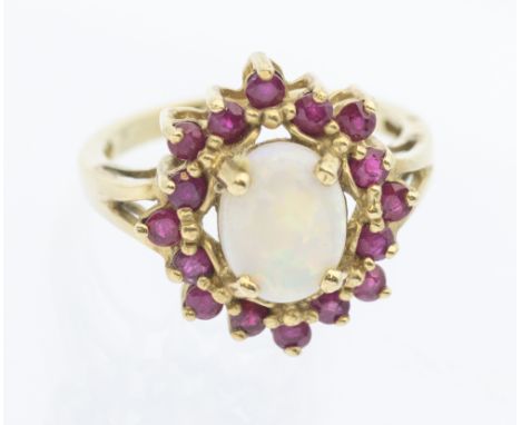 An opal and ruby set 9ct gold cluster ring, comprising a central oval opal, within a claw set border of round rubies, width a