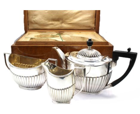 A matched late Victorian Scottish silver three piece tea set, all of oval form with gadrooned bodies, tea pot with ebonised h