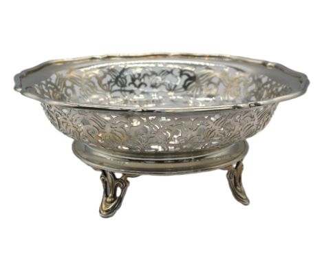 A George V silver bowl, having pierced foliate and floral design with scrolled edging and upon a circular base with four elab