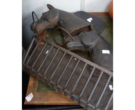 A PAIR OF CAST IRON HORSES HEADS, 30cm high and a cast iron wall hung planter, in the form of an animal feeder (3)