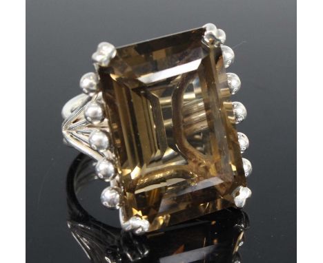 A contemporary white metal and smoky quartz set dress ring, the emerald cut quartz measuring approx 28 x 20 x 14mm, in a rais