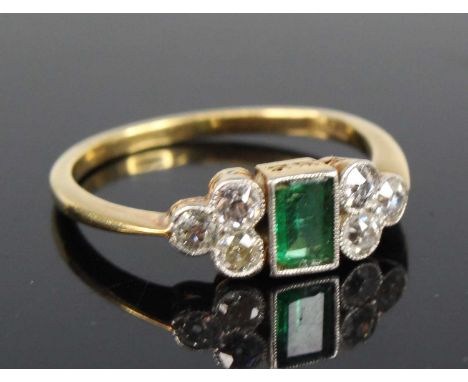 A yellow metal, emerald and diamond ring, comprising a centre rectangular cut emerald with a trefoil of Old European cut diam