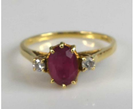 An 18ct yellow and white gold, synthetic ruby and diamond three-stone ring, comprising an oval synthetic ruby with a round br