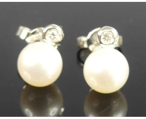 A pair of white metal pearl and diamond stud earrings, each featuring a 6.9mm Akoya cultured pearl suspended below a 1.9mm ro