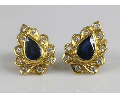 A pair of yellow metal sapphire and diamond leaf shaped cluster earrings, each with a centre pear cut sapphire within a borde