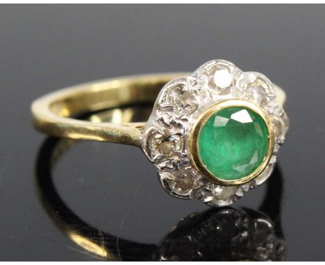 An 18ct yellow and white gold, emerald and diamond circular cluster ring, featuring a centre round emerald within a halo of e