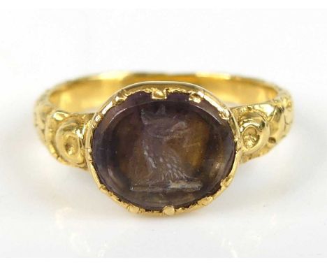 A yellow metal engraved ring, comprising an oval quartz intaglio engraved with a dragon's head, stone dimensions approx 8.8 x