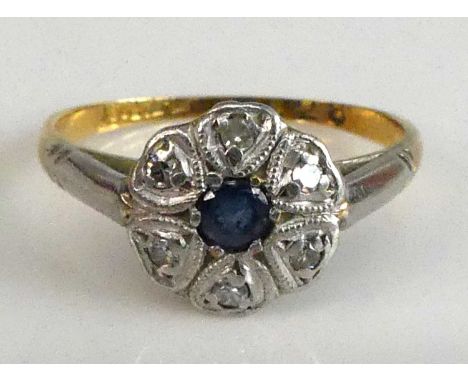 A yellow and white metal, sapphire and diamond circular cluster ring, featuring a centre round sapphire within a border of si