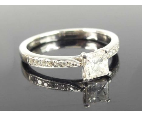 A platinum diamond solitaire ring, comprising a Princess cut diamond in a four-claw setting with seven graduated brilliant cu