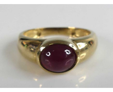 A 9ct yellow gold ruby dress ring featuring an oval ruby cabochon in a bezel setting. Ruby dimensions 8.3 by 6.85 by 4.25mm. 