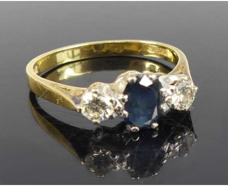 An 18ct yellow and white gold, sapphire and diamond three-stone ring, featuring a centre oval sapphire with a round brilliant