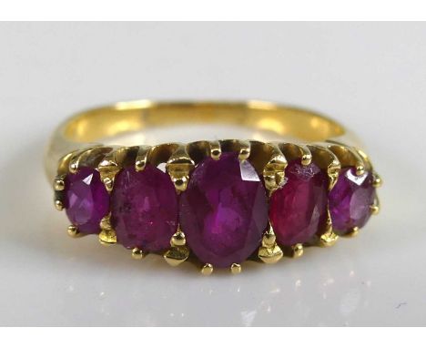 A yellow metal ruby half hoop eternity ring with 5 graduated oval rubies in scalloped claw settings. Ruby dimensions between 