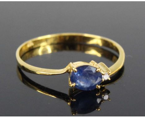 A contemporary yellow metal, sapphire and diamond ring, the four-claw set oval cut sapphire weighing approx 0.3 carats, flank