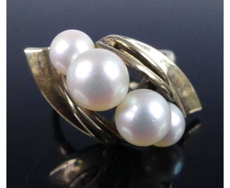 A continental yellow metal cultured pearl set dress ring, arranged as four rows of graduated pearls in a raised abstract sett