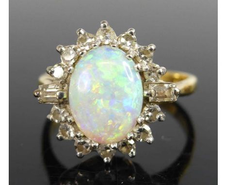 A yellow and white metal opal and diamond oval cluster ring featuring a centre oval cabochon within a border of 14 single and