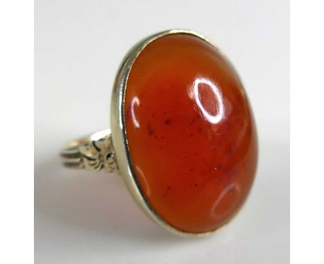 A yellow metal carnelian dress ring, the oval carnelian measuring 20.55 by 15.2mm approx. Mounted in a bezel setting with scr