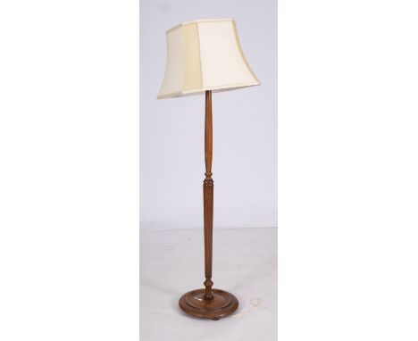 A stained hardwood standard lamp, 20th century; with reeded column and fabric shade; 160cm high overall