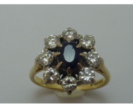 AN 18CT GOLD SAPPHIRE AND DIAMOND RING, the oval shape sapphire within a surround of brilliant-cut diamonds, estimated total 
