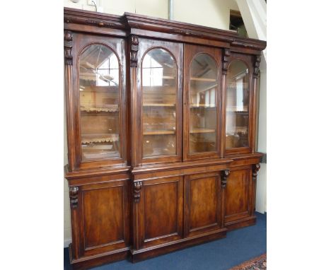 A VICTORIAN MAHOGANY BREAKFRONT BOOKCASE, with Ogee cornice above four arch glazed panel doors enclosing shelves divided by a