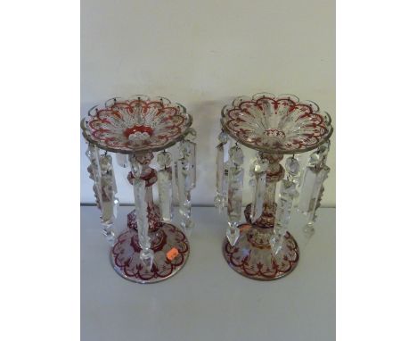 A PAIR OF RUBY STAINED LUSTRES, circa 1890, the faceted baluster stems with broad lobed trumpet rims and domed feet decorated