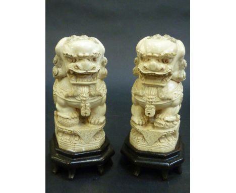 A PAIR OF CHINESE CARVED IVORY FIGURES OF LION DOGS, early 20th Century, seated on double lotus bases and with carved hardwoo