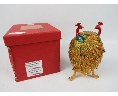 A large enamel and crystal encrusted trinket box of ovoid form depicting a pair of peacocks, raised on tripod supports, appro