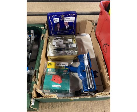 A box containing a small mitre saw, a tin containing drill measure stoppers, drill depth controller, chisel, angle grinder, p