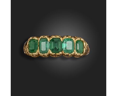 A late Victorian emerald five stone ring, set with graduated emerald-cut emeralds in scrolling yellow gold mount, size N