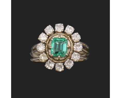 A French emerald and diamond cluster ring, the emerald-cut emerald is set within a surround of round brilliant-cut diamonds i