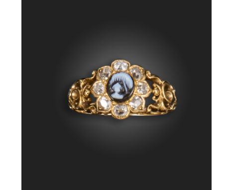 A mid 19th century gold mourning ring, set with a banded agate cameo depicting an urn within diamond border and gold scrollin