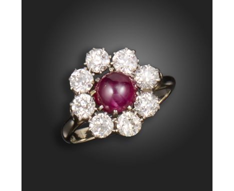 A ruby and diamond cluster ring, the ruby cabochon is set within a surround of old circular-cut diamonds in silver on gold, s