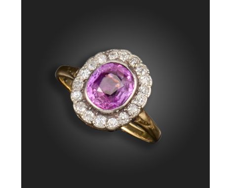 A pink sapphire and diamond cluster ring, the oval-shaped sapphire is set within a surround of cushion-shaped diamonds in sil