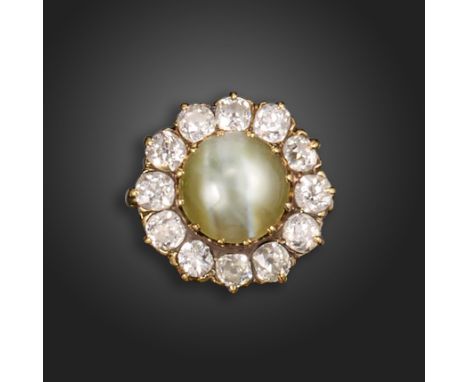 A chrysoberyl catseye and diamond cluster ring, the cabochon chrysoberyl catseye set within a surround of old circular-cut di