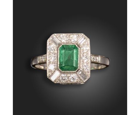 An emerald and diamond cluster ring, the emerald-cut emerald set within a surround of round brilliant-cut diamonds and quarte