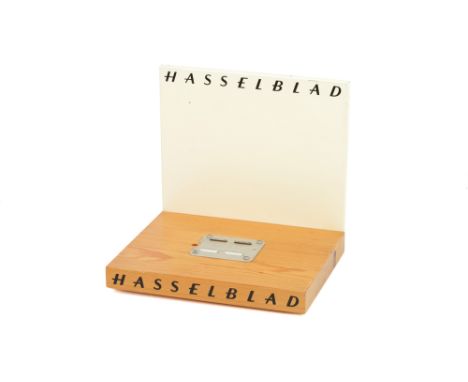 A Hasselblad 500C Camera Display Stand, with wooden base and painted wooden back, marked to base 'Made in Sweden'