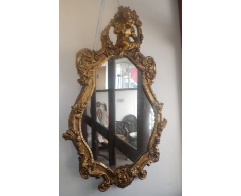 A 19TH CENTURY RECOCO GILT GESSO AND CARVED WOOD WALL MIRROR, with putti finial, 38" x 24.5"