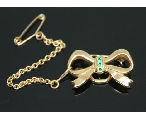 A 9ct gold emerald brooch of bow form, sponsor's mark 'CG&amp;S', length 22mm, gross wt. 3.63g.  Condition - slight kink in p