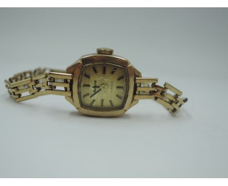 A 9ct gold wrist watch by Accurist having baton numeral dial to square champagne face with 9ct gold case and gate bracelet st
