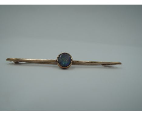 A rose gold bar brooch stamped 9ct having central black opal in collared mount, approx 2g