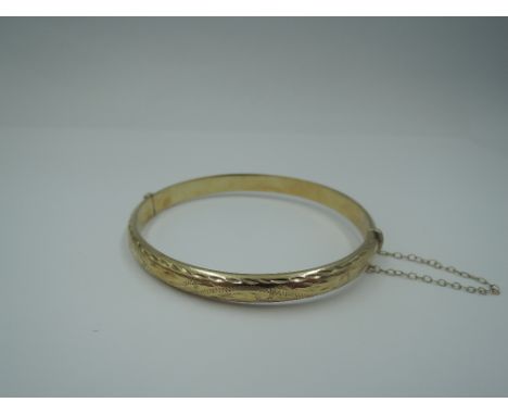 A 9ct gold hinged bangle having engraved decoration, approx 8.3g