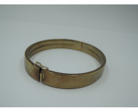 A yellow metal hinged bangle of plain form stamped 333 having concealed clasp and safety clip, approx 1806g