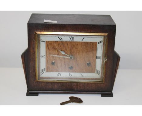 An Art Deco period wooden cased mantle clock with key. (needs attention) 